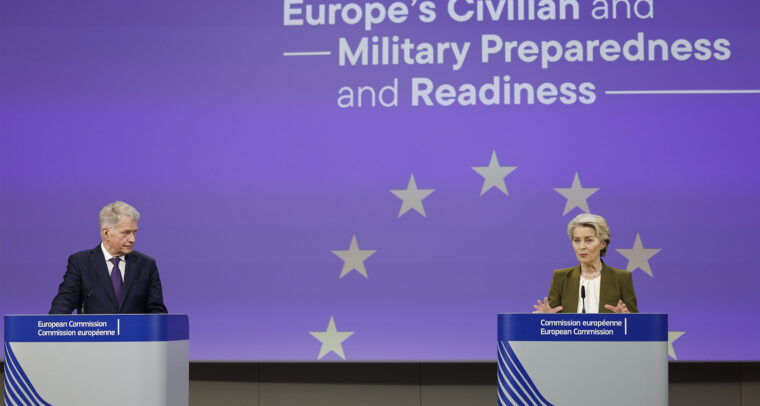 El expresidente de Finlandia, Sauli Niinistö, a la izquierda, y la presidenta de la Comisión Europea, Ursula von der Leyen, a la derecha en la rueda de prensa de presentación del Informe Niinistö. Ambos se encuentra de pie en podios frente a un fondo azul con estrellas amarillas que representan la bandera de la UE y el texto en inglés 'Strengthening Europe’s Civilian and Military Preparedness and Readiness', ‘’Refuerzo de la preparación civil y militar de Europa’’, en español. Niinistö