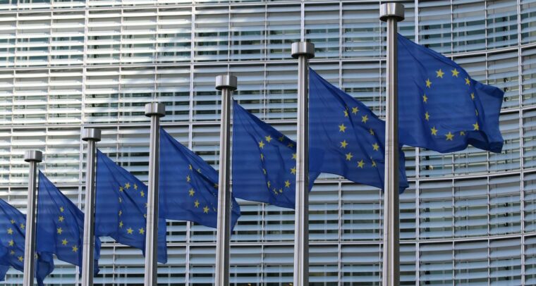 Seven flags of the European Union, with blue background and yellow stars, flying in front of the European Commission headquarters in Brussels (Belgium) during the day. Middle East