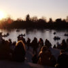 Sunset at the Retiro Park Lake (Madrid) with visitors relaxing and boats on the water. Spain