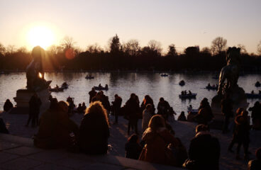 Sunset at the Retiro Park Lake (Madrid) with visitors relaxing and boats on the water. Spain