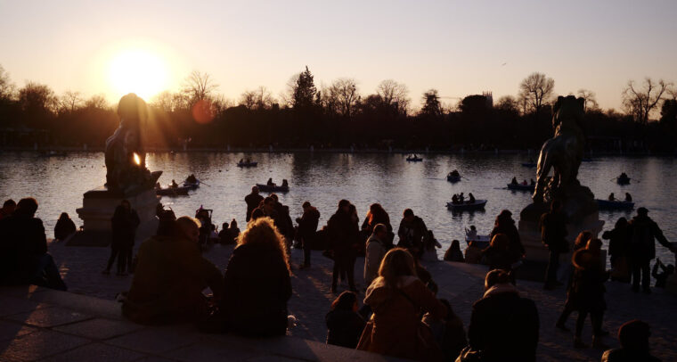 Sunset at the Retiro Park Lake (Madrid) with visitors relaxing and boats on the water. Spain