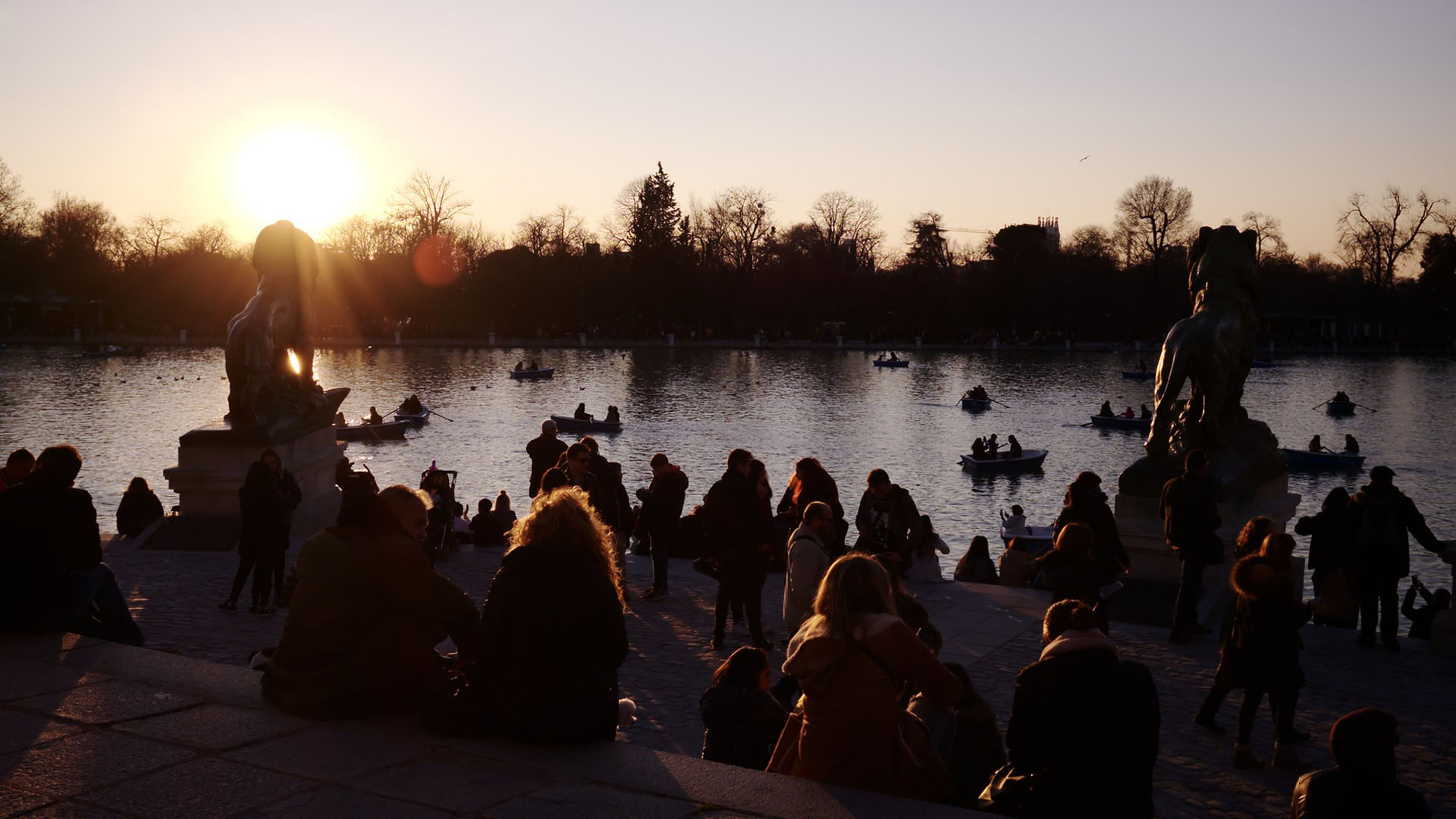 Sunset at the Retiro Park Lake (Madrid) with visitors relaxing and boats on the water. Spain