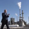 Donald Trump camina aplaudiendo frente a la refinería Andeavor en Mandan, Dakota del Norte (EEUU), con chimeneas liberando vapor o humo al fondo, en un día despejado. Trump