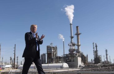 Donald Trump camina aplaudiendo frente a la refinería Andeavor en Mandan, Dakota del Norte (EEUU), con chimeneas liberando vapor o humo al fondo, en un día despejado. Trump