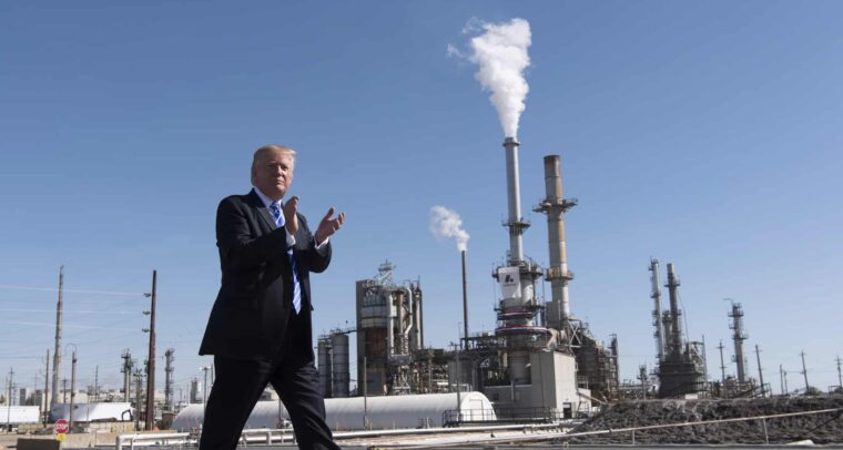 Donald Trump camina aplaudiendo frente a la refinería Andeavor en Mandan, Dakota del Norte (EEUU), con chimeneas liberando vapor o humo al fondo, en un día despejado. Trump