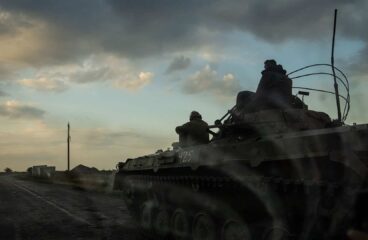 Tanque militar ucraniano en movimiento al atardecer, con dos soldados a bordo, avanzando por una carretera rural en la región de Pokrovsk en Ucrania. Ucrania