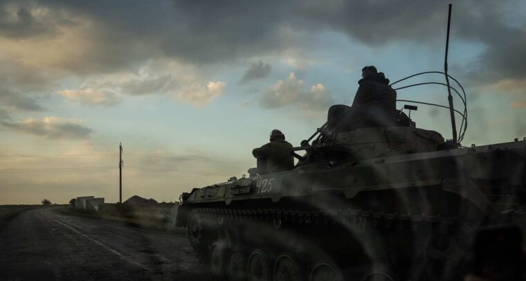 Tanque militar ucraniano en movimiento al atardecer, con dos soldados a bordo, avanzando por una carretera rural en la región de Pokrovsk en Ucrania. Ucrania