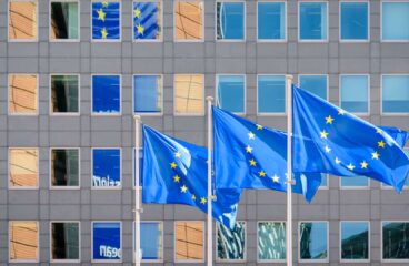 Three European Union (EU) flags fly in the wind at full mast outside the windows of the Berlaymont building, the headquarters of the European Commission (the EU executive) in Brussels, Belgium