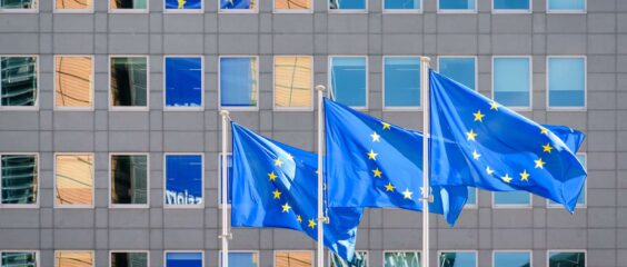 Three European Union (EU) flags fly in the wind at full mast outside the windows of the Berlaymont building, the headquarters of the European Commission (the EU executive) in Brussels, Belgium