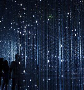 Silhouettes of people observing an interactive art installation with bright LED lights in a dark setting. Digital priorities