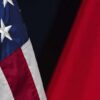 Primer plano de las banderas de Estados Unidos y China, parcialmente visibles sobre un fondo oscuro. La bandera de Estados Unidos muestra estrellas blancas sobre azul y franjas rojas y blancas, mientras la de China presenta fondo rojo con una estrella amarilla. Geopolítica