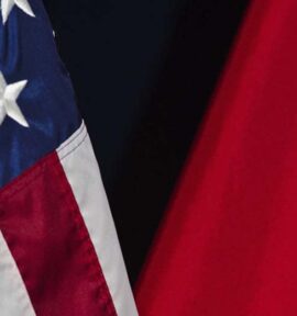 Primer plano de las banderas de Estados Unidos y China, parcialmente visibles sobre un fondo oscuro. La bandera de Estados Unidos muestra estrellas blancas sobre azul y franjas rojas y blancas, mientras la de China presenta fondo rojo con una estrella amarilla. Geopolítica