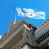 Low view of the façade of the building of the Central Bank of the Argentine Republic with a blue and white Argentine flag flying under a clear sky. Stabilisation plan