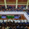 Detalle de la Cumbre de Presidentes de los Estados Partes y Estados Asociados del Mercosur en Montevideo (Uruguay), donde los participantes están sentados alrededor de una gran mesa de conferencias en una sala formal, con las banderas de los países del Mercosur al fondo, el 6 de diciembre de 2024. UE-Mercosur