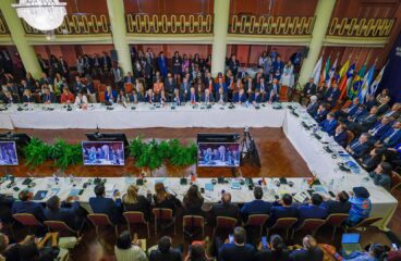 Detail of the Summit of Presidents of the Member States and Associate States of MERCOSUR in Montevideo (Uruguay), where participants are seated around a large conference table in a formal room, with the flags of MERCOSUR countries in the background, on 6 December 2024. EU-Mercosur