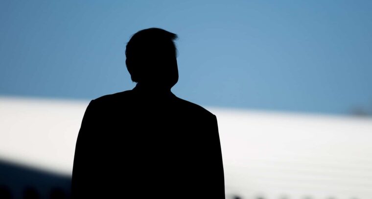 En primer plano, se aprecia la silueta de Donald Trump durante la ceremonia de presentación del Boeing 787-10 en Carolina del Sur, Estados Unidos. Al fondo, se distingue el perfil de un avión blanco bajo un cielo azul en pleno día.