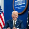 Joe Biden (sentado, con un traje azul, camisa blanca y corbata de rayas azules y amarillas) durante una llamada virtual con simpatizantes para conmemorar el primer aniversario de su administración, el miércoles 19 de enero de 2022, en el Auditorio South Court del Edificio de Oficinas Ejecutivas Eisenhower de la Casa Blanca. Detrás, la bandera de EEUU y el logo oficial de la Casa Blanca