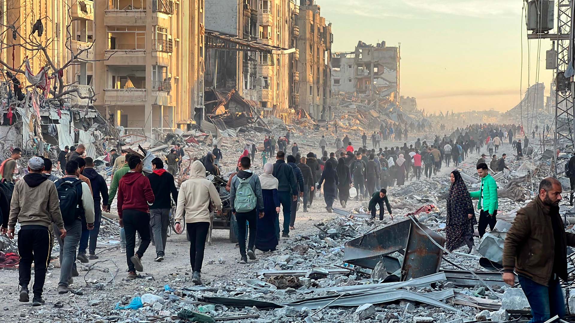 Palestinos caminan entre los escombros de edificios destruidos mientras regresan a sus hogares tras el anuncio de un alto al fuego y un acuerdo de intercambio de rehenes y prisioneros entre Hamás e Israel en Jabalia (Gaza), el 19 de enero de 2025. Alto el fuego