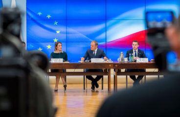 Reunión oficial de la Conferencia de Presidentes del Parlamento Europeo con el primer ministro polaco Donald Tusk y representantes del gobierno de Polonia. En el fondo, se observa una pantalla con la bandera de la Unión Europea y la bandera de Polonia, mientras los participantes dialogan en torno a una mesa en un entorno institucional. Presidencia