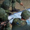 Maniobras militares durante la visita de la presidenta Tsai al condado de Pingtung (Taiwán). En primer plano, tres soldados, vestidos con uniforme militar y casco, observan un mapa. Al fondo, se distingue de forma difusa el brazo de un soldado más. Taiwán