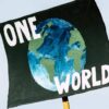 Hand-painted poster for the global climate change protest demonstration strike. On a black background, the representation of a globe in shades of green and blue with the words ‘One World’