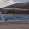 Vista del Centro de Recepción e Identificación de usos múltiples cerca de Lakki, en la isla de Leros (Grecia). El centro, rodeado por una valla de seguridad, se encuentra en una colina, desde donde se divisa el mar en primer plano y un cielo nublado al fondo. Migración