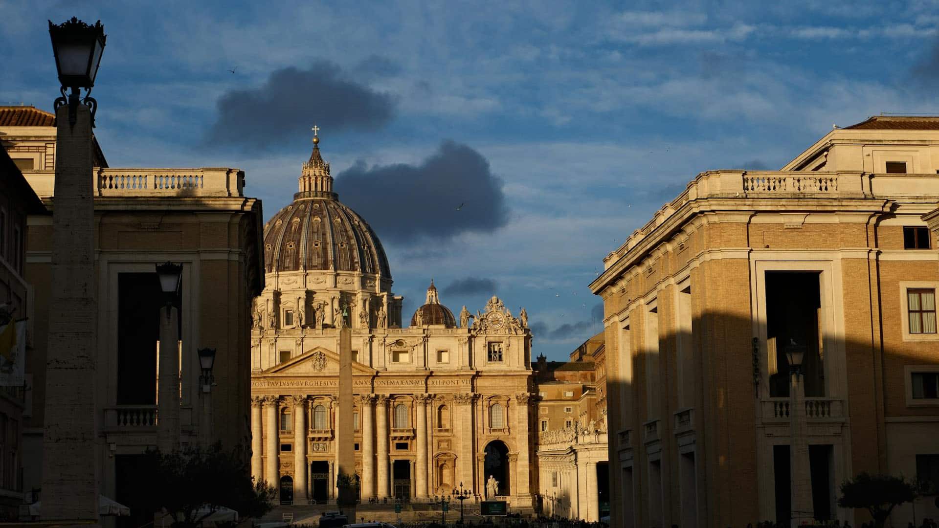 Fachada de la Basílica de San Pedro iluminada por la luz dorada del atardecer en la Ciudad del Vaticano. Cónclave