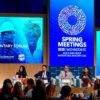 Panel internacional en el Global Parliamentary Forum 2025 durante las Reuniones de Primavera del Banco Mundial y el FMI en Washington D.C. A la izquierda, de pie, un hombre modera el panel desde el podio, mientras seis panelistas debaten frente a una audiencia diversa. Las pantallas LED muestran logotipos del evento y rostros de diferentes personas. Reuniones de primavera