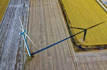 Vista aérea de una turbina eólica proyectando sombra sobre campos agrícolas parcialmente cubiertos de nieve en el Dodge Center de Minnesota (Estados Unidos). Trump