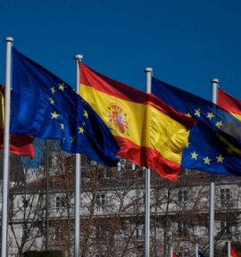 Banderas de España y de la Unión Europea ondeando en la plaza de Cánovas del Castillo (Plaza de Neptuno) en Madrid. Tras los árboles, el edificio del Hotel Ritz. Foto: acho Arenas (CC BY-NC-SA 2.0).