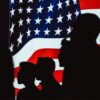 Siluetas humanas delante de una bandera de Estados Unidos en una pantalla iluminada. Estados Unidos