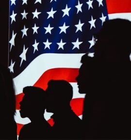 Siluetas humanas delante de una bandera de Estados Unidos en una pantalla iluminada. Estados Unidos