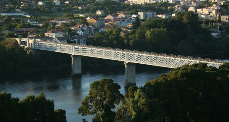 Puente internacional de estructura metálica con diseño de celosía, apoyado sobre pilares de hormigón, que cruza el río Miño conectando las localidades de Tuy (España) y Valença do Minho (Portugal), rodeado de paisaje urbano y vegetación. Europa
