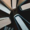 Vista cenital de varios libros abiertos, dispuestos en círculo, mostrando los cantos de las páginas y las cubiertas. Libros