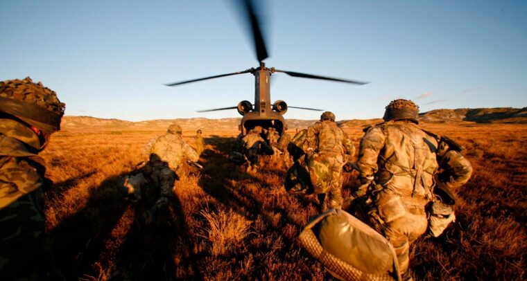 Soldados del Ejército de Tierra español corren hacia un helicóptero con las hélices en movimiento, durante un ejercicio militar en el campo. España