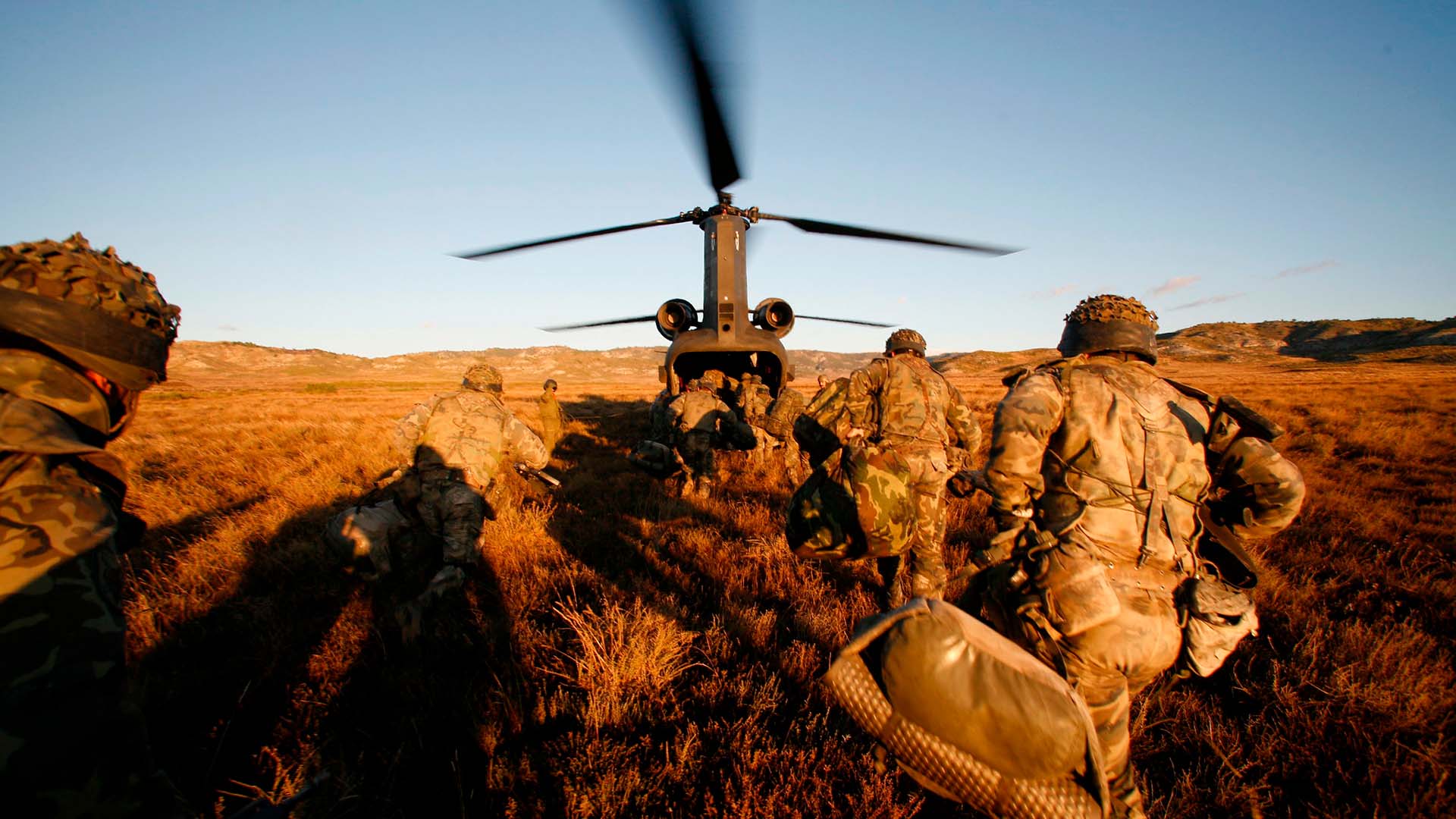 Soldados del Ejército de Tierra español corren hacia un helicóptero con las hélices en movimiento, durante un ejercicio militar en el campo. España