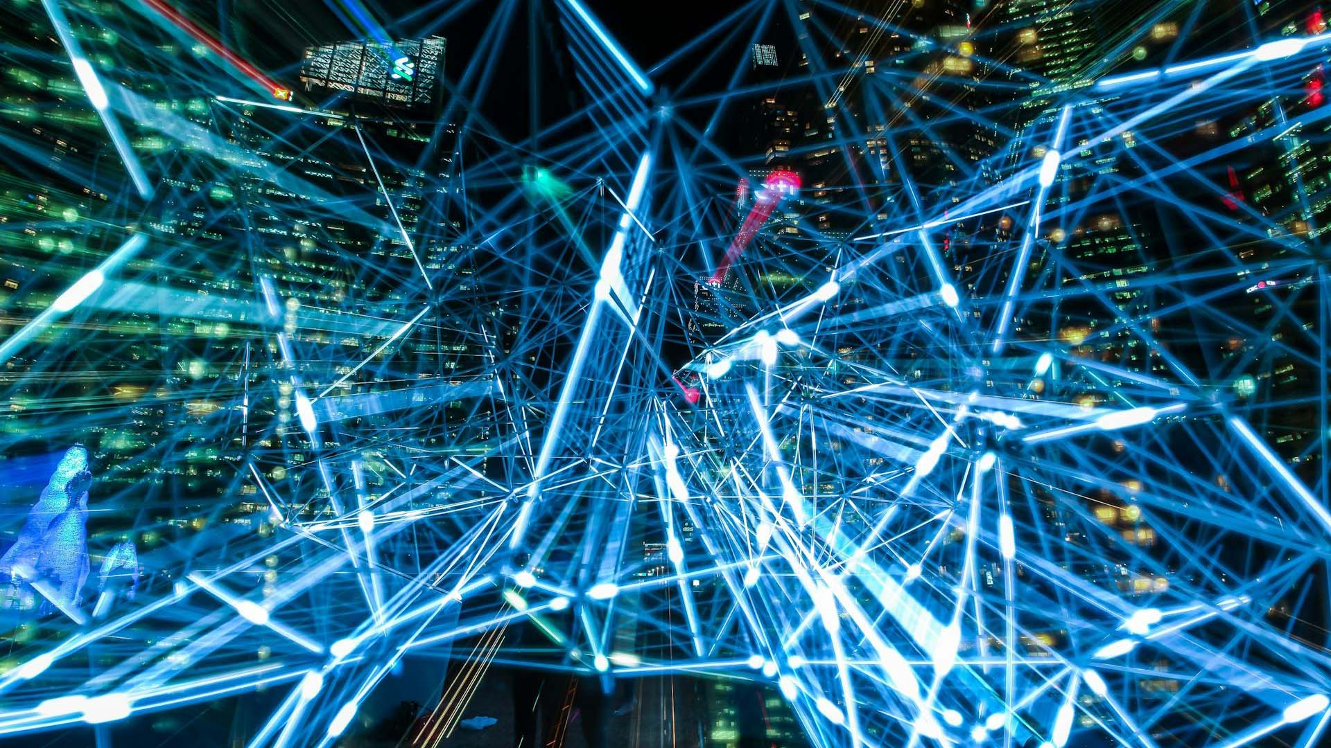 Conexiones de datos digitales azules y brillantes, superpuestas sobre una ciudad moderna de noche. Digital