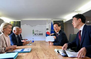 Six people in formal attire sit around a wooden table in a conference room at the G7 Summit in Canada on 17 June 2025. In the background, a sign with the text “G7 + 2025 Kananaskis” and the flags of the Republic of Korea and the European Union. Among those attending the meeting: Lee-Jae Myung (President of the Republic of Korea, second on the right), Ursula von der Leyen (President of the European Commission, first on the left) and Antonio Costa (President of the European Council, second on the left).