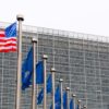 Fachada de la Comisión Europea en Bruselas con banderas de la Unión Europea alineadas y una bandera de Estados Unidos ondeando en primer plano en un día nublado. Acuerdo