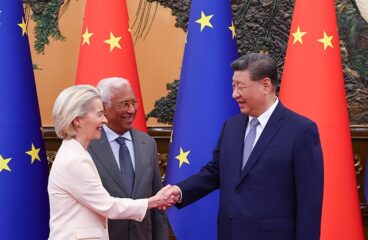 Ursula von der Leyen, presidenta de la Comisión Europea (a la izquierda) estrechando manos con Xi Jinping, presidente de China (a la derecha), mientras los observa Antonio Costa, presidente del Consejo Europeo (al lado de von der Leyen) durante la Cumbre UE-China en Pekín (24 de julio de 2025). Al fondo, las banderas de la Unión Europea (azules con estrellas amarillas) y de China (rojas con estrellas amarillas).