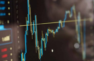 Close-up of a monitor showing blue and yellow financial graphs. Tax