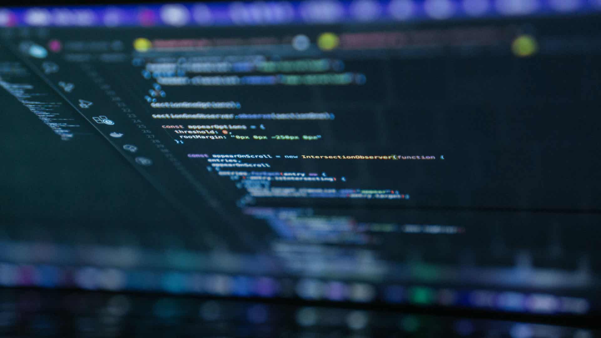 Líneas de código en la pantalla de un ordenador portátil con texto resaltado en naranja, azul, blanco y verde sobre un fondo oscuro. Código abierto