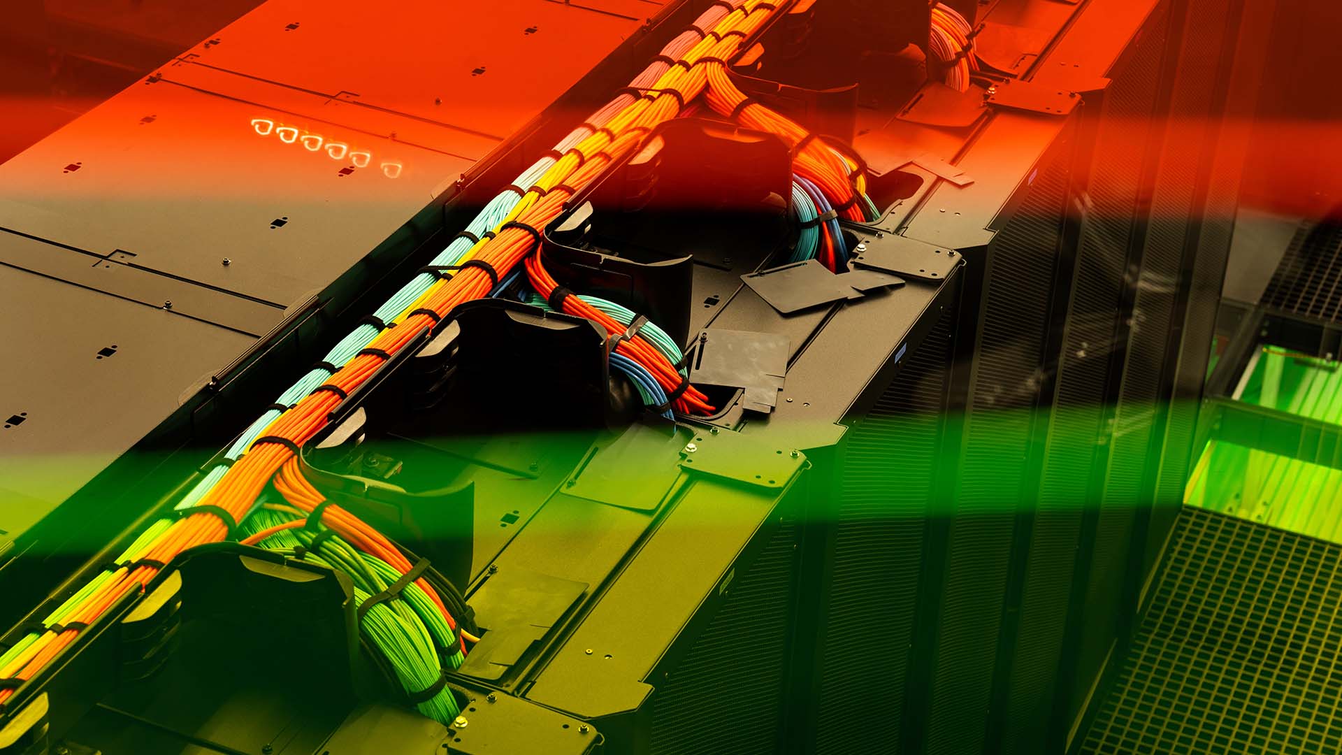 Detalle del cableado multicolor de alta velocidad del superordenador MareNostrum 5 del Barcelona Supercomputing Center, organizados en bandejas de cableado conectadas al centro de datos, con filtro de tonos rojos y verdes.