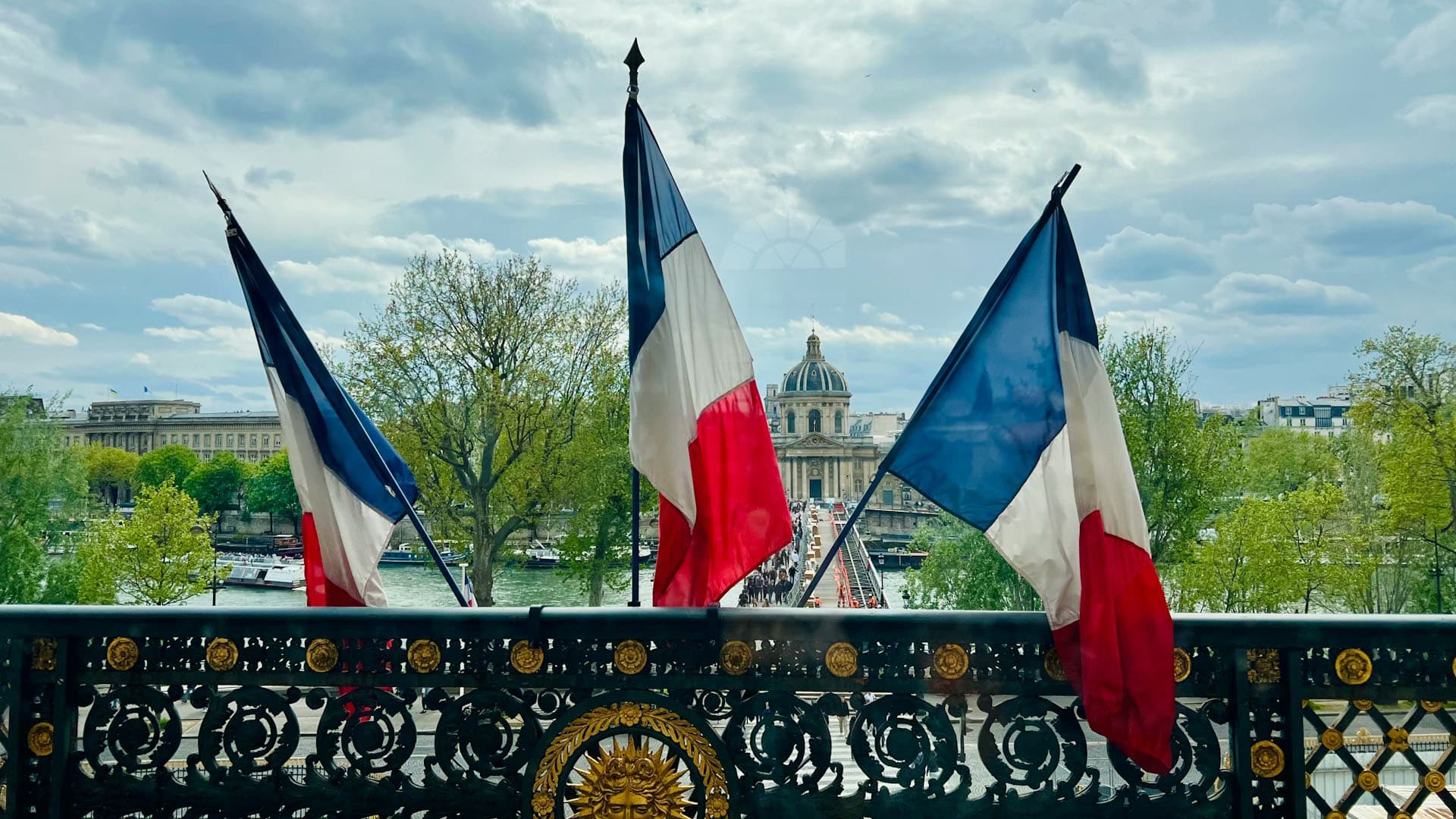 Tres banderas de Francia expuestas una baranda en la entrada al Museo del Louvre en París.