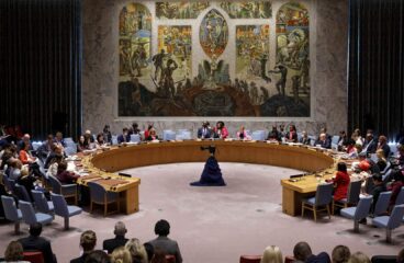 Miembros del Consejo de Seguridad de la ONU reunidos alrededor de una mesa circular en la sala de conferencias con un mural al fondo, para debatir sobre la Agenda de Mujeres, Paz y Seguridad (Nueva, York, 2022).