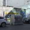 Propaganda electoral y graffitis en una calle de Buenos Aires (Argentina) en 2023. En primer plano, coches aparcados y al centro un container de basura con la leyenda “Si la patria sos vos hacete cargo”. En la pared de detrás, un cartel de Santiago Cúneo, candidato presidencial que promete una Argentina “a lo Bukele”, y a la derecha el cartel de Alejandro Biondini (h), candidato del partido neonazi Bandera Vecinal.