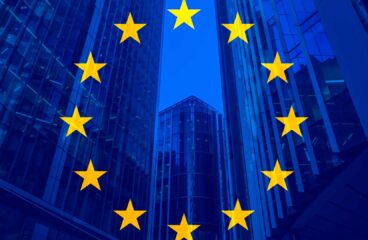 Flag of the European Union against a backdrop of modern glass buildings.