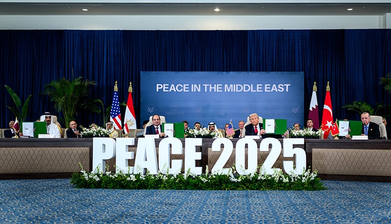 Ceremonia de firma del acuerdo de alto el fuego entre Israel y Hamás para el fin a la guerra en Gaza durante la cumbre en Sharm el Sheij (Egipto). En primer plano las palabras “Peace 2025”, en la mesa sentados sosteniendo las carpetas del acuerdo con sus firmas (de izquierda a derecha): Tamim bin Hamad al Thani (emir de Qatar), Abdelfatah al-Sisi (presidente de Egipto), Donald Trump (presidente de EEUU) y Recep Tayyip Erdoğan (presidente de Turquía). Al fondo las banderas de EEUU, Egipto, Qatar y Turquía, el resto de líderes mundiales, y una pantalla con las palabras “Peace in the Middle East”.
