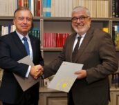 Francisco Botas Ratera, consejero delegado de ABANCA, estrecha la mano de José Juan Ruíz, presidente del Real Instituto Elcano, en un despacho frente a una biblioteca