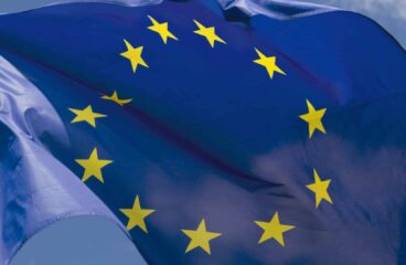 La bandera de la Unión Europea ondea en primer plano (27/06/2018) sobre un cielo claro y despejado.